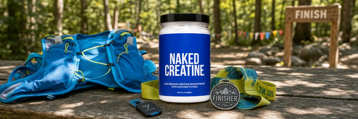 Naked Creatine tub beside a trail running vest, finisher medal, and timing chip on a wooden picnic table
