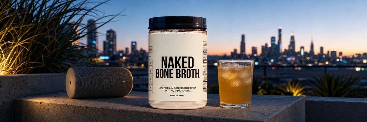 Naked Bone Broth protein powder tub on rooftop terrace at blue hour with city skyline