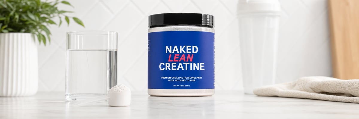 Naked Lean Creatine tub on an Olympic lifting platform next to a barbell and lifting belt